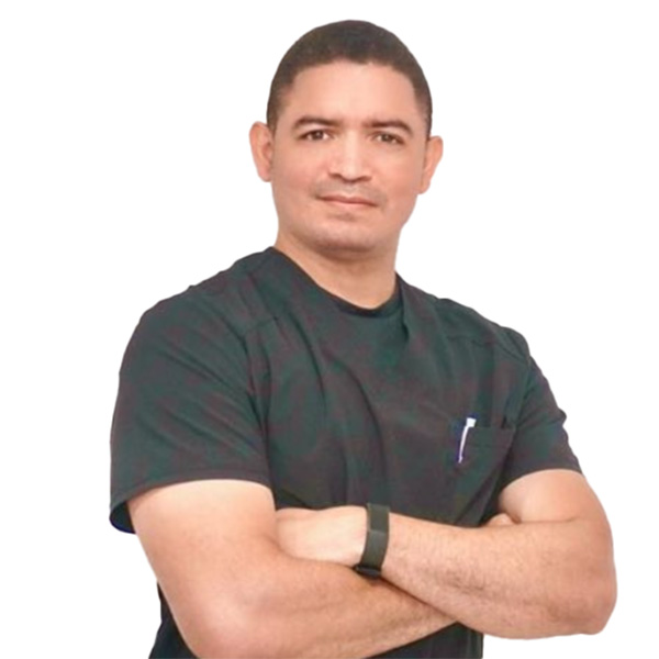 Un hombre con pelo corto, camiseta negra y brazos cruzados mira confiado a la cámara, sobre un fondo blanco liso, reflejando la profesionalidad y confianza típica de un especialista en ortopedia deportiva.Doctor profesional en ortopedia deportiva con actitud confiada y uniforme negro.